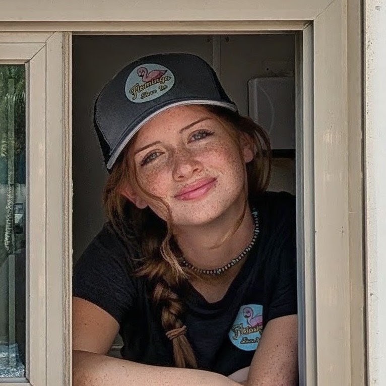 Aubrey smiling with a peace sign from the Flomingo Shave Ice trailer window